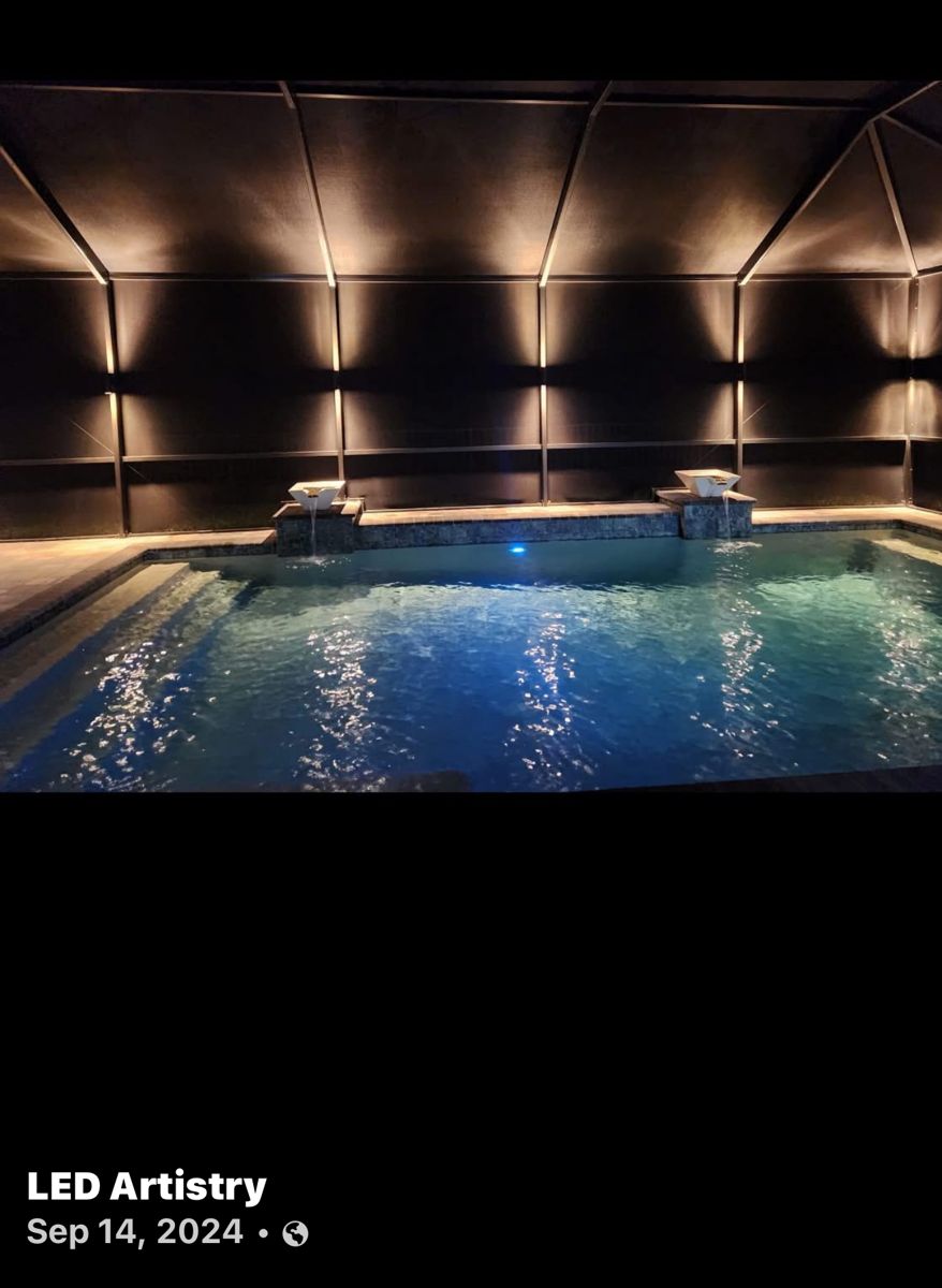 Pool cage with warm LED perimeter lighting on screen enclosure framing at night