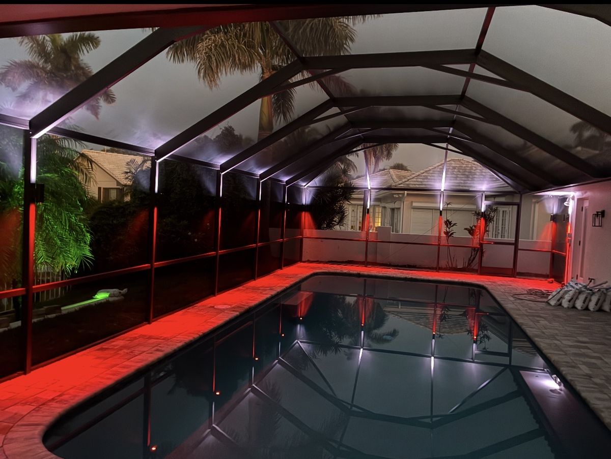 Pool cage with dramatic red RGBW LED color lighting at night, pool reflection Tampa Bay