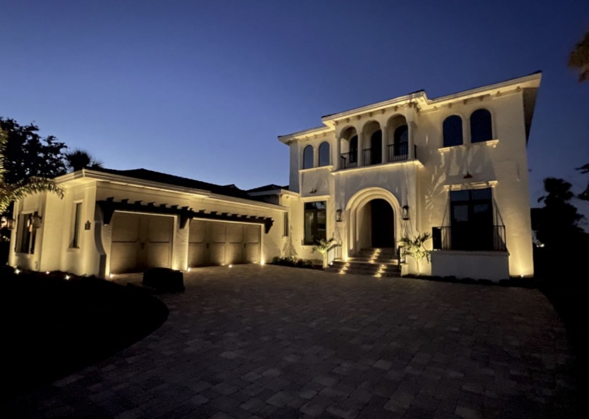 Large luxury home with paver driveway and full architectural LED uplighting at night